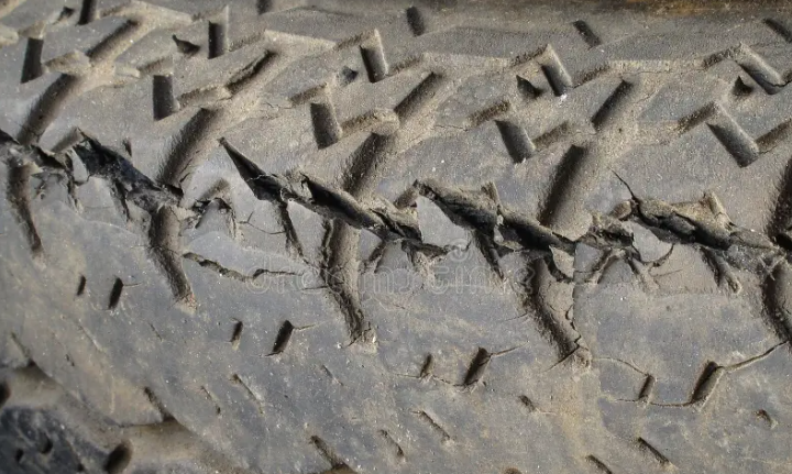 Close-up of a rubber track surface with deep transverse cracks running across the tread